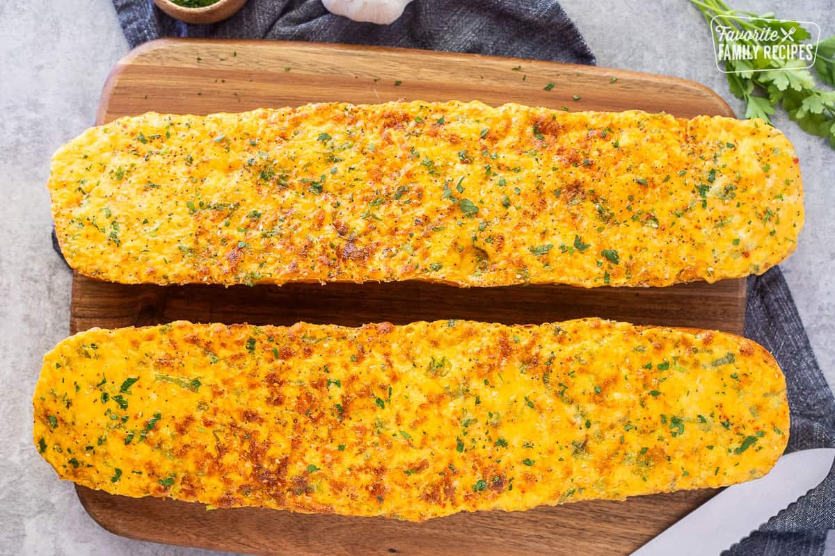 Baked French bread with garlic bread spread on cutting board.