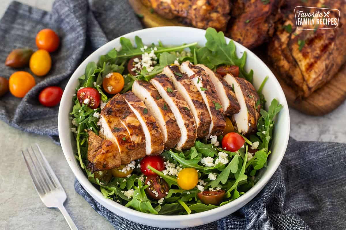 Sliced grilled balsamic chicken on an arugula salad.