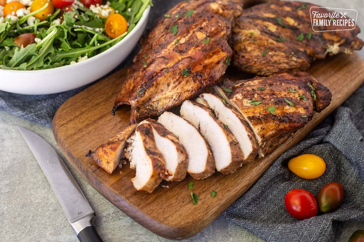 Sliced grilled balsamic chicken on a cutting board.