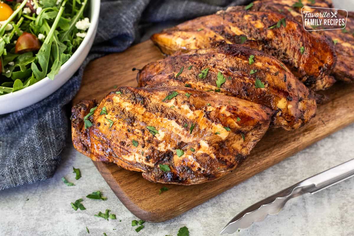 Grilled balsamic chicken on a cutting board and garnished with parsley.