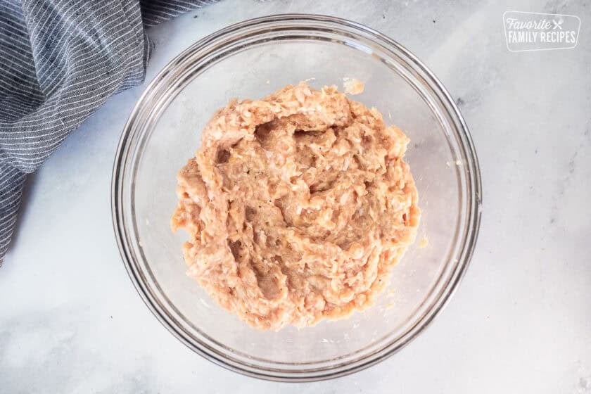 Glass mixing bowl with ground chicken mixture.