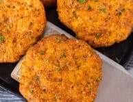 Spatula removing a ground chicken patty from a plate of ground chicken patties.