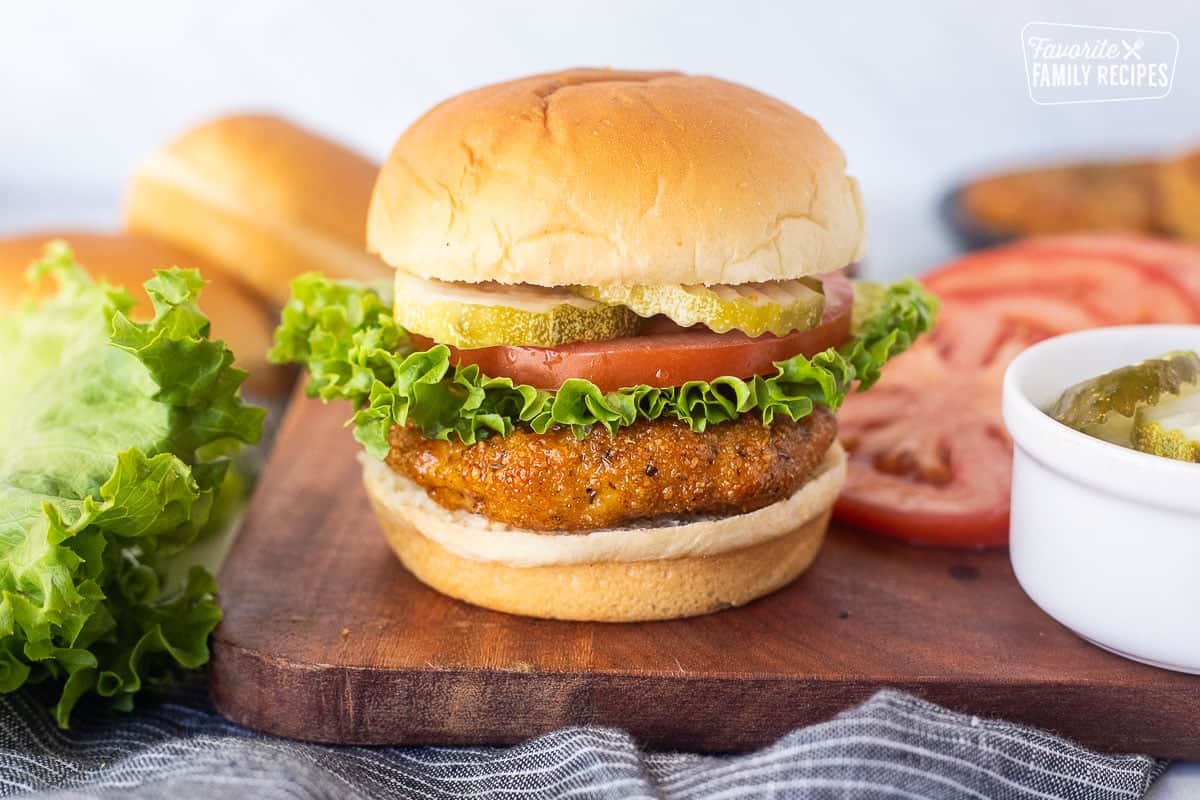 Ground chicken patty sandwich with lettuce, tomato and pickles on a bun.