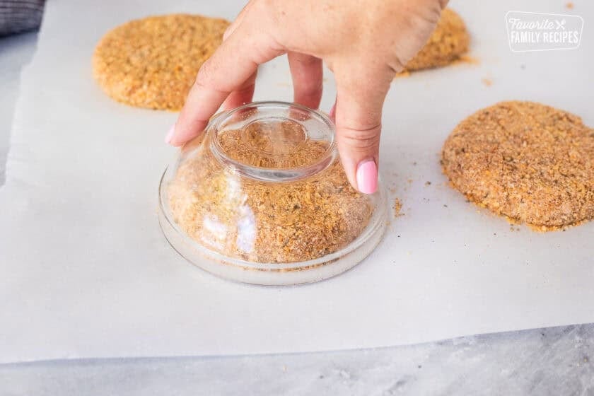 Using a cup upside down over a raw ground chicken patty to shape it circular.