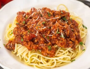 Ground turkey spaghetti on a plate with pasta topped with sauce.