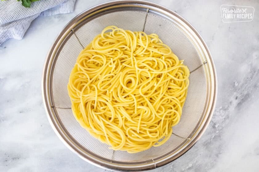 Colander with drained cooked spaghetti pasta.