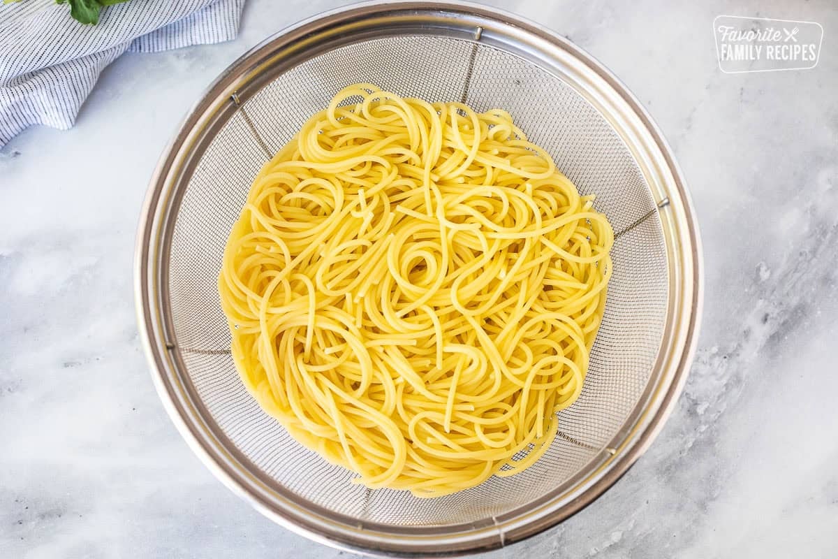 Colander with drained cooked spaghetti pasta.