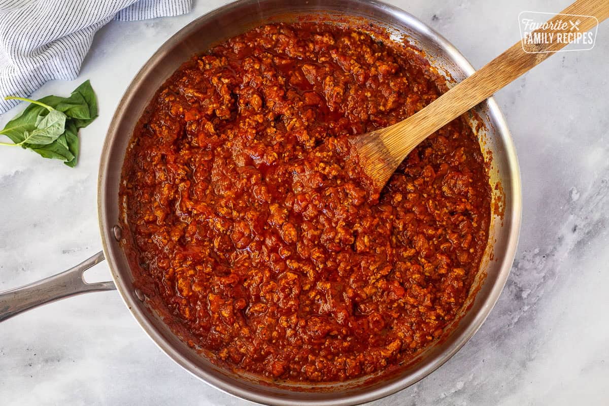 Skillet of ground turkey spaghetti sauce and wooden spoon.