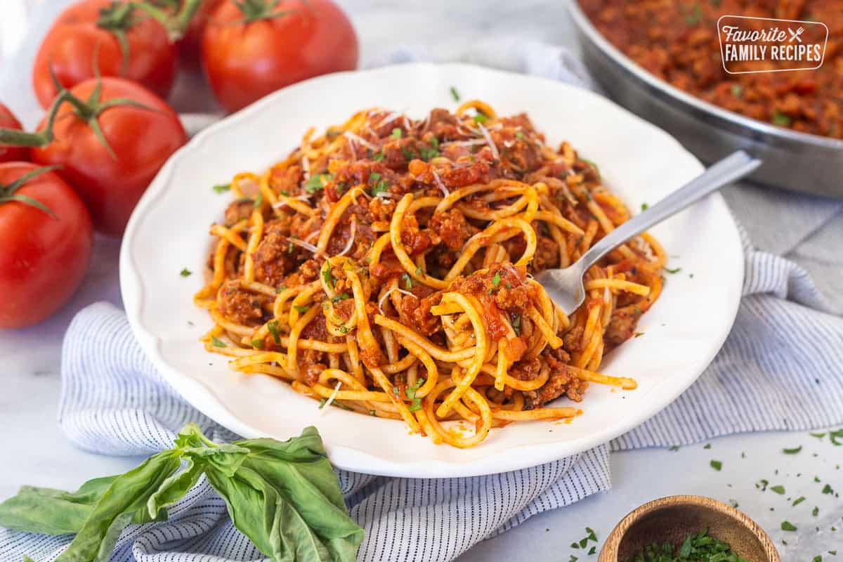 Ground turkey spaghetti twirled around a fork and resting on plate of ground turkey spaghetti.