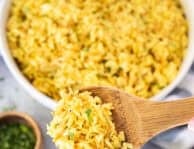 Wooden spoon with homemade Rice-A-Roni garnished with parsley.