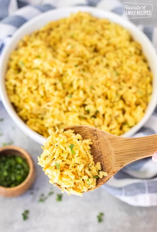 Wooden spoon with homemade Rice-A-Roni garnished with parsley.