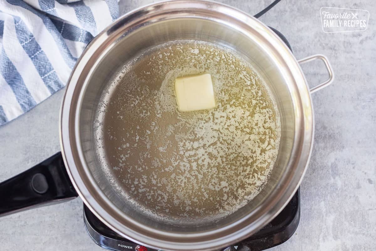Saucepan melting butter over an electric skillet.