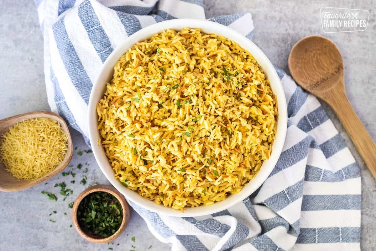 Bowl of homemade Rice-A-Roni garnished with parsley and wooden spoon on the side.