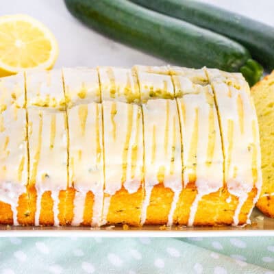 Sliced lemon zucchini bread loaf with glaze on a plate.