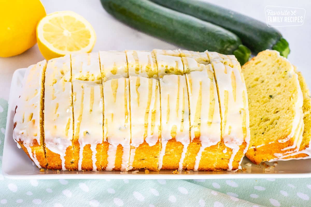 Sliced lemon zucchini bread loaf with glaze on a plate.