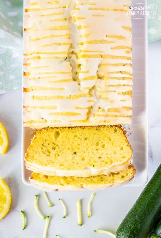 Glazed lemon zucchini bread loaf with slices on a plate.
