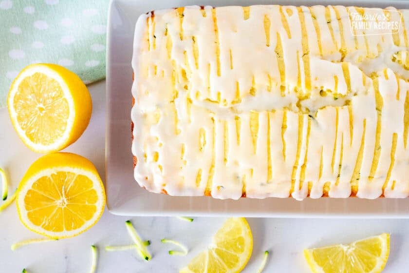 Whole glazed lemon zucchini bread loaf on a plate.