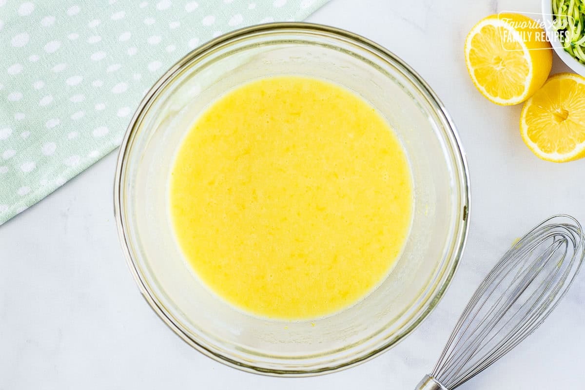 Glass mixing bowl with egg mixed with sugar and lemon juice.