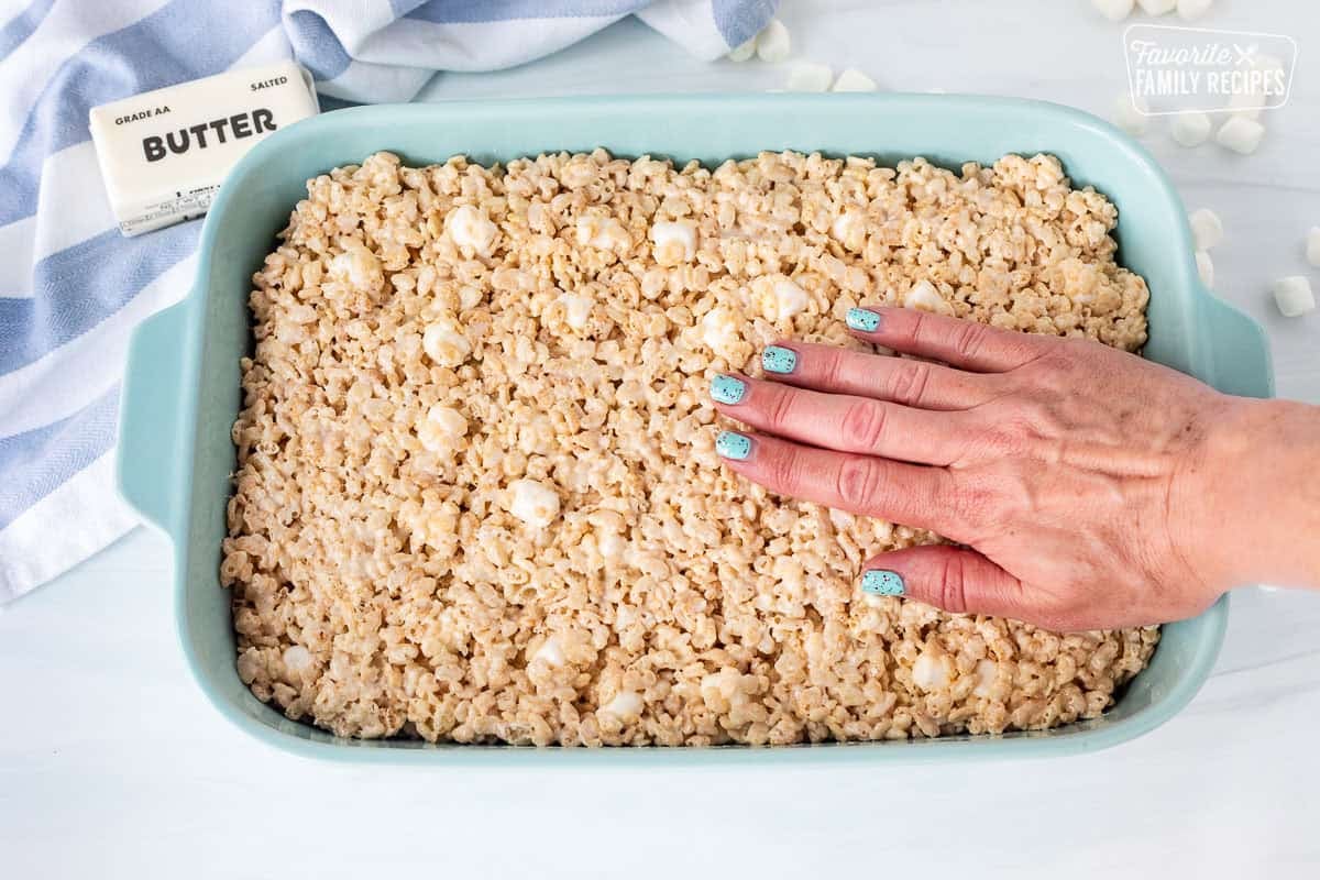 Pressing Rice Krispie treats into pan with hand.
