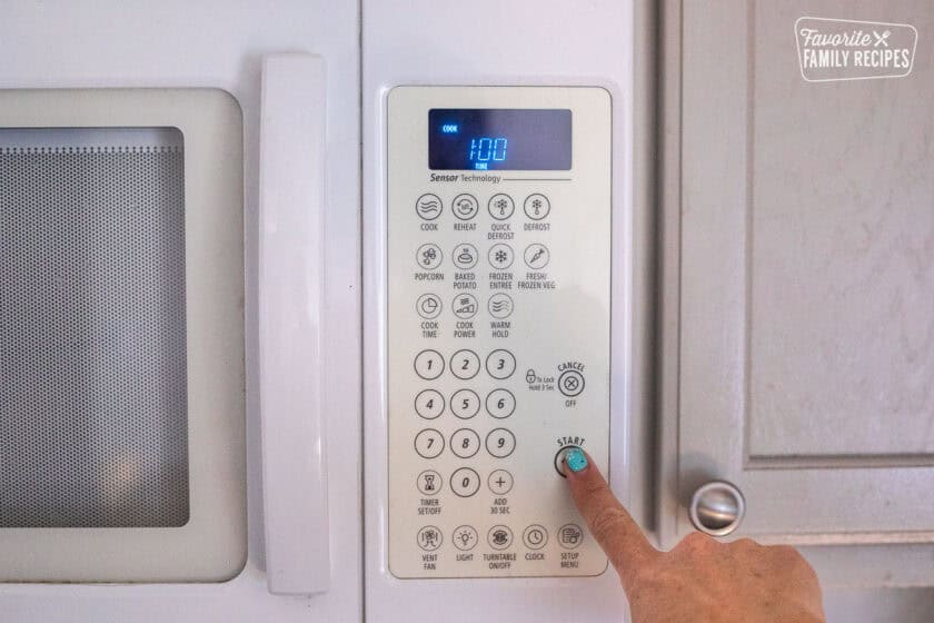 Hand pressing one minute on a microwave.