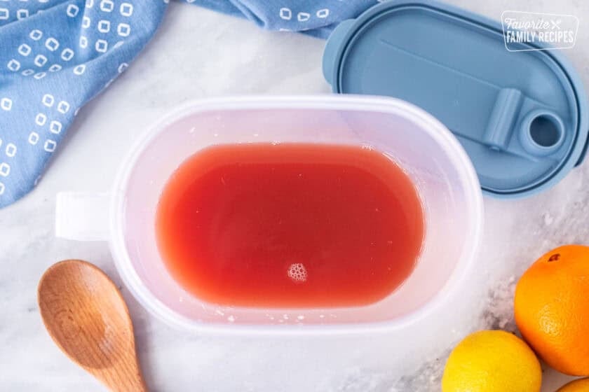 Pitcher with lid containing party punch juice and wooden spoon on the side.