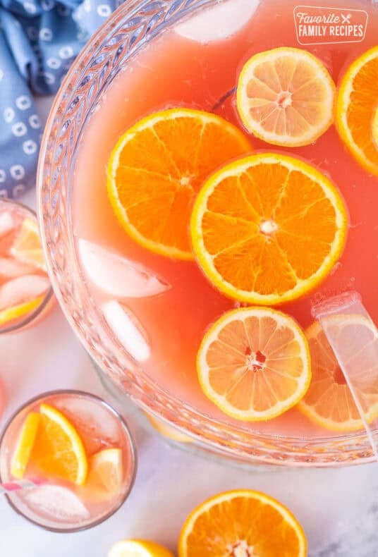 Ladle resting in a bowl of party punch with fresh lemon slices and orange slices.