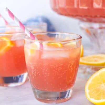 Glasses of party punch with ice and fresh slices of oranges and lemons with a straw.
