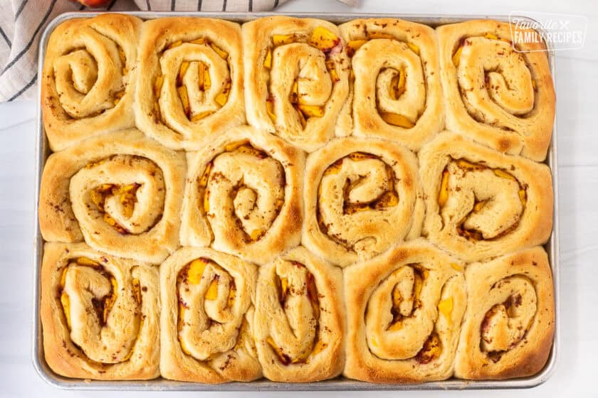 Sheet pan with baked peach cinnamon rolls.