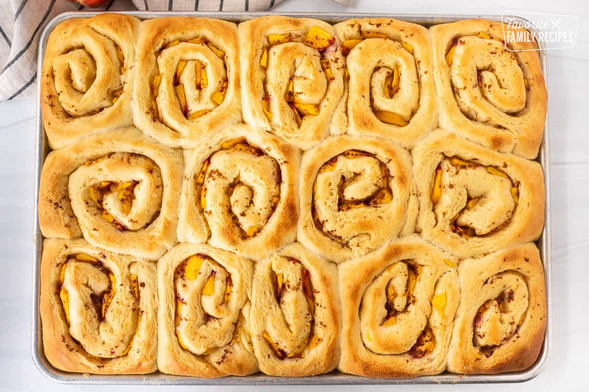 Sheet pan with baked peach cinnamon rolls.