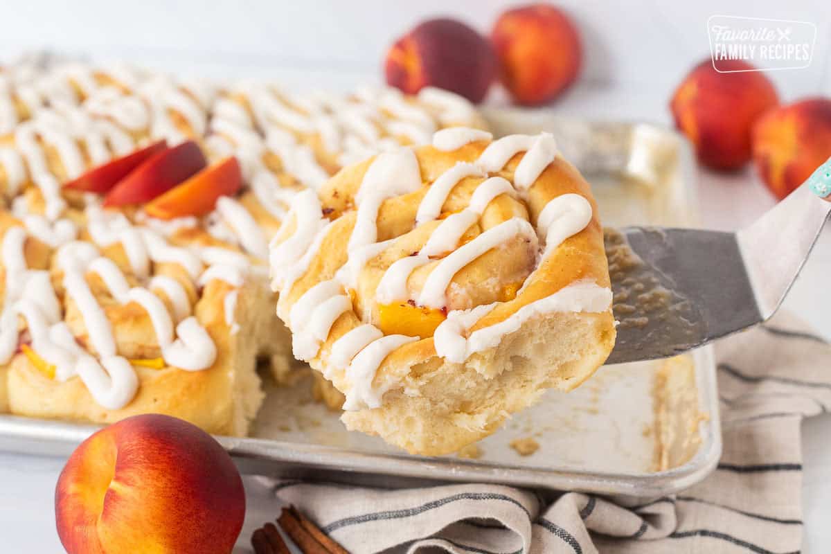 Spatula with a peach cinnamon roll from sheet pan.