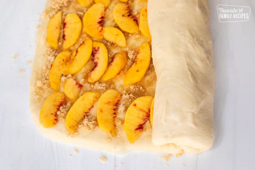 Rolling up peach cinnamon rolls.