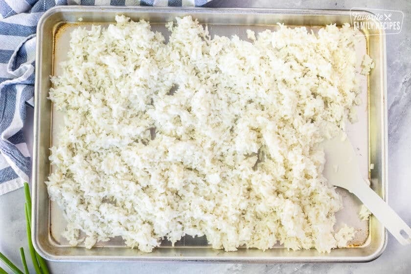 Cooling cooked rice on a baking sheet.