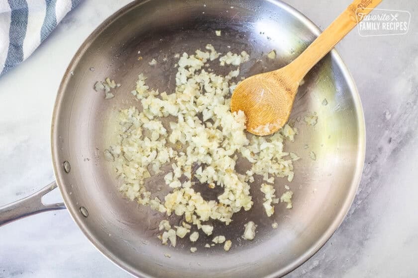 Skillet with translucent onion and wooden spoon.