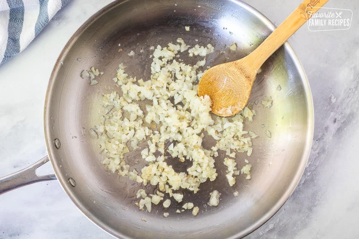 Skillet with translucent onion and wooden spoon.