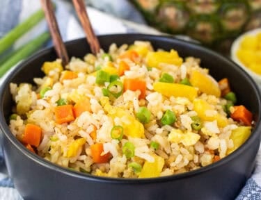 Pineapple fried rice in a bowl with rice, pineapple, carrots, peas and green onion.