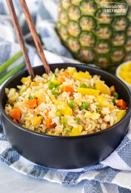 Pineapple fried rice in a bowl with rice, pineapple, carrots, peas and green onion.