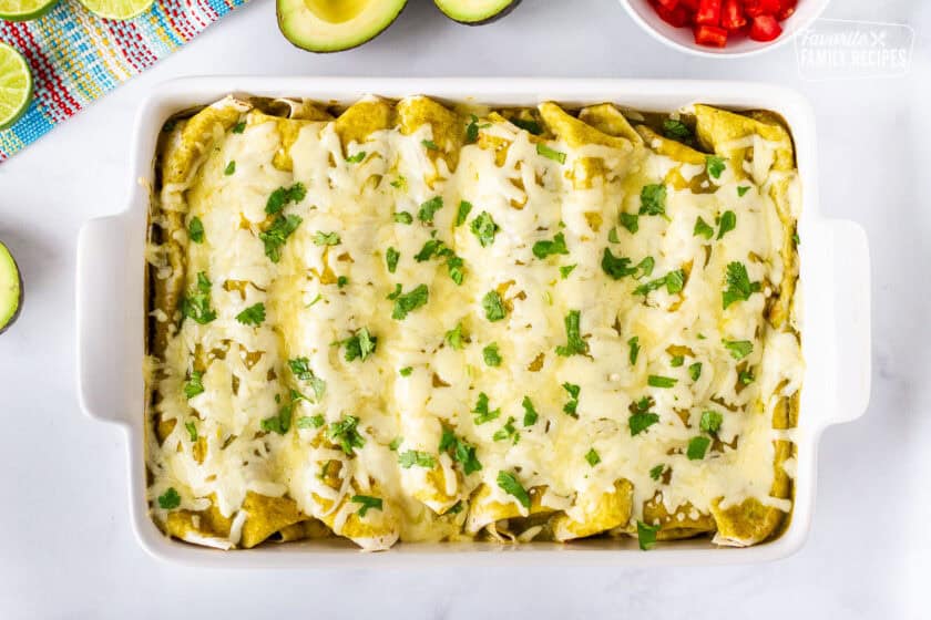 Baking dish with baked spinach enchiladas and garnished with cilantro.
