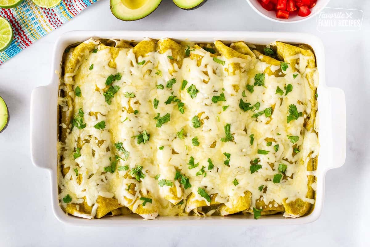 Baking dish with baked spinach enchiladas and garnished with cilantro.