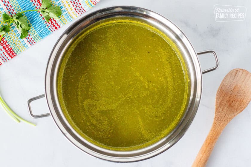 Saucepan with green sauce and wooden spoon on the side.