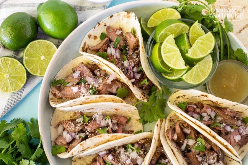 Close up of Street Tacos with limes, cilantro and red onions.