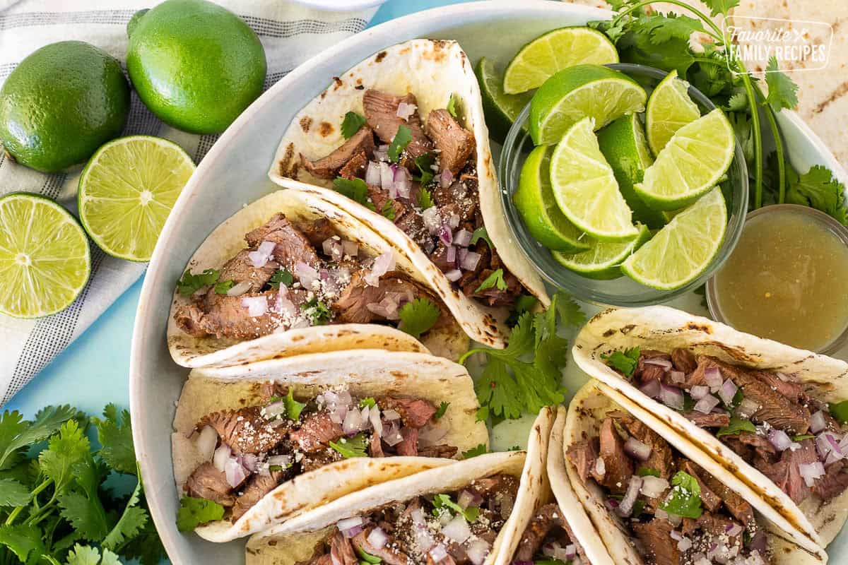 Close up of Street Tacos with limes, cilantro and red onions.