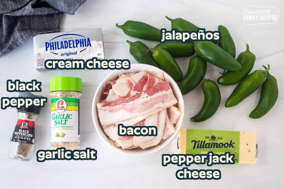 Ingredients to make bacon wrapped jalapeño poppers including jalapeños, pepper jack cheese, bacon, cream cheese, garlic salt and black pepper.