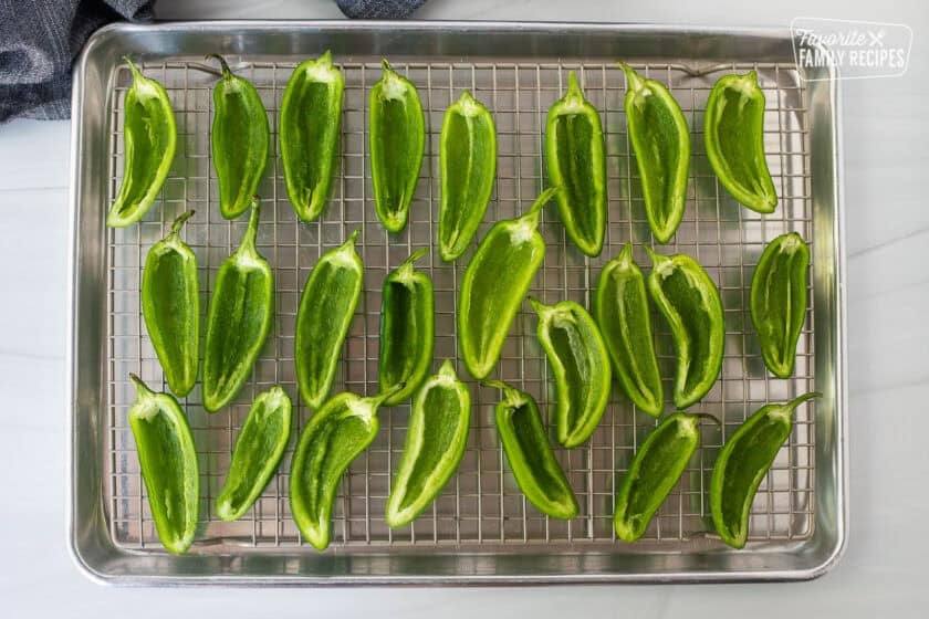 Sliced and scooped out fresh jalapeños on a sheet pan with wire rack.