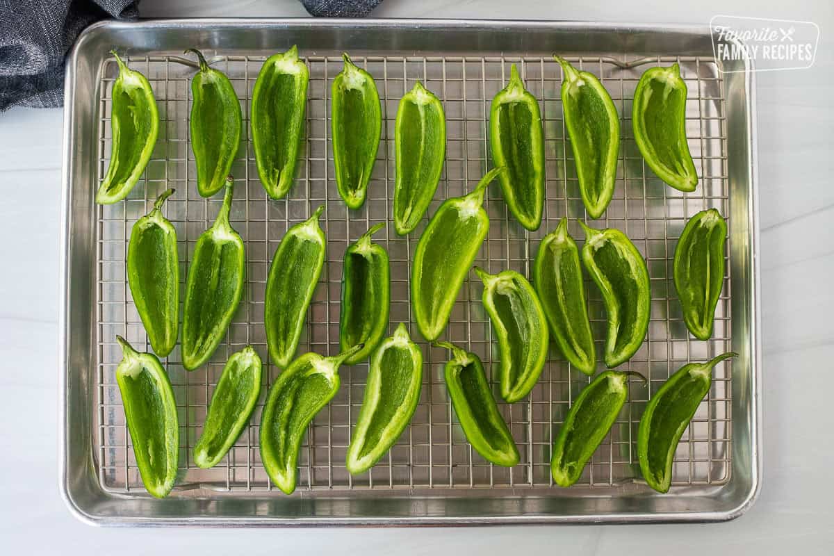 Sliced and scooped out fresh jalapeños on a sheet pan with wire rack.