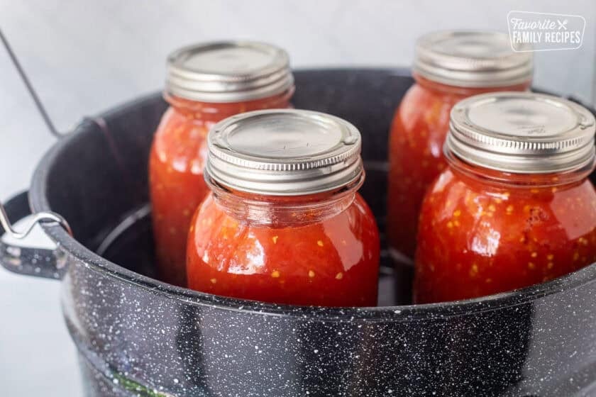 Four jars of canned diced tomatoes in a canning pot.
