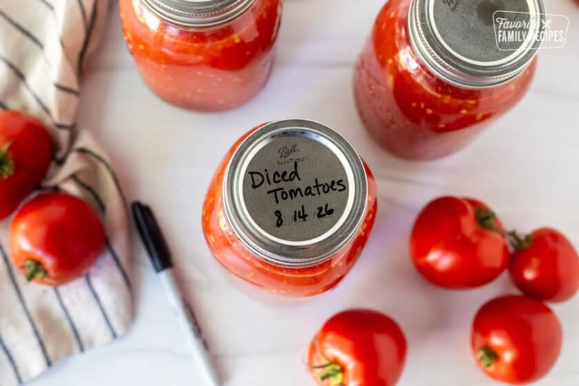 Writing diced tomatoes and date on the top of a canning jar.