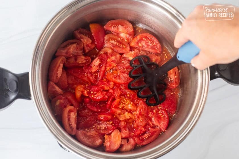 Squishing tomatoes in a large pot.