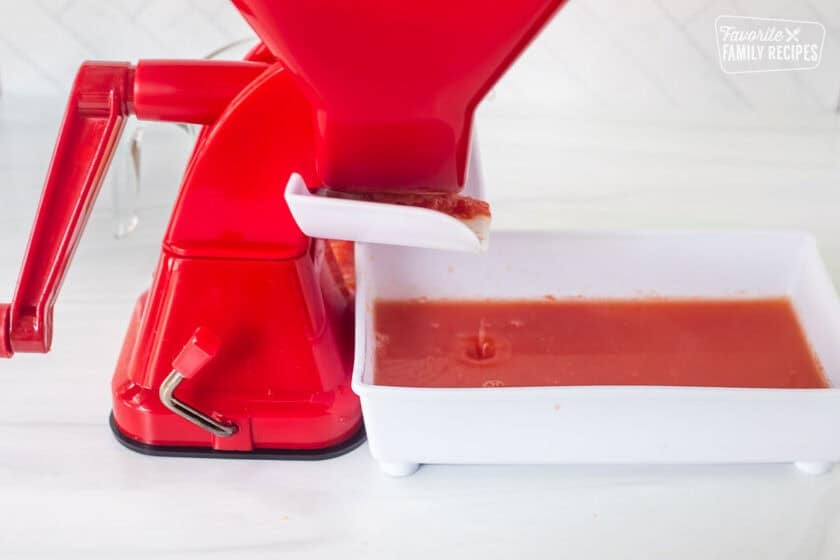 Straining cooked tomatoes in a tomato juicer .