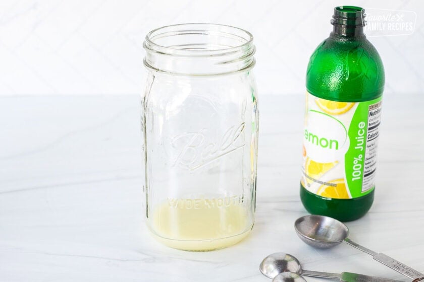 Canning jar with lemon juice and measuring spoons.