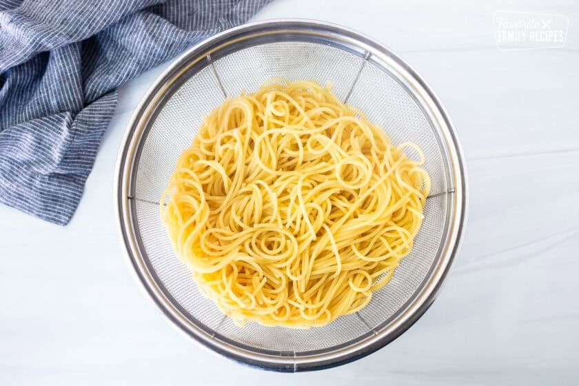 Cooked spaghetti pasta in colander.